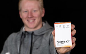 Male athlete holding Ketone-IQ box.