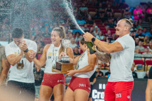 Team Invictus member spraying champagne on the rest of the team during their CrossFit Games podium celebration.