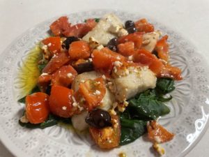 Air fryer fish topped with tomatoes and other veggies.