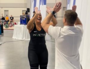 Female Olympic lifter and her coach giving the double-high five to each other.